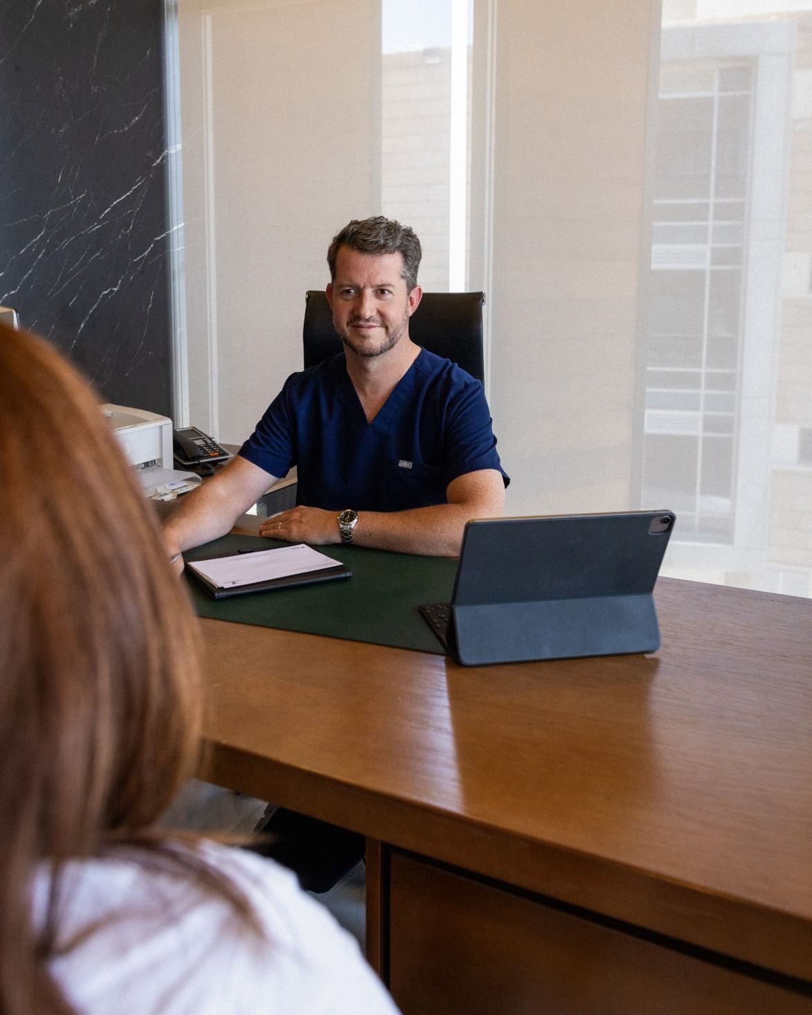 El Dr. Rodrigo Fernández escucha a una paciente en su consultorio